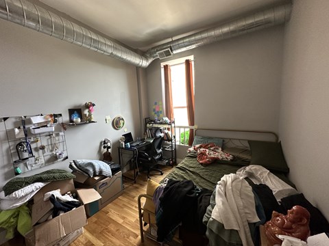 A room with a bed, desk, and clutter.