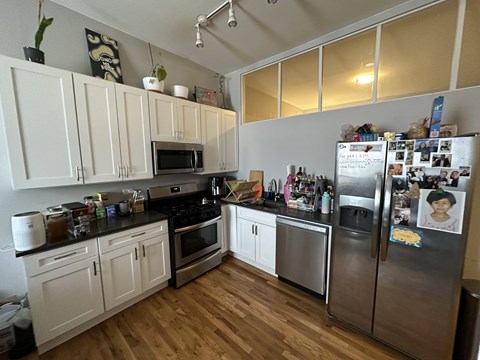 A kitchen with white cabinets and a fridge filled with magnets.