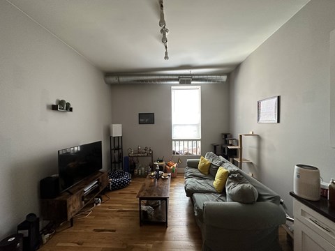 A living room with a grey couch and a wooden floor.