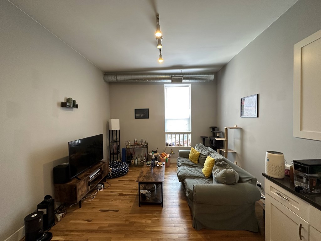 A living room with a grey couch and a wooden floor.