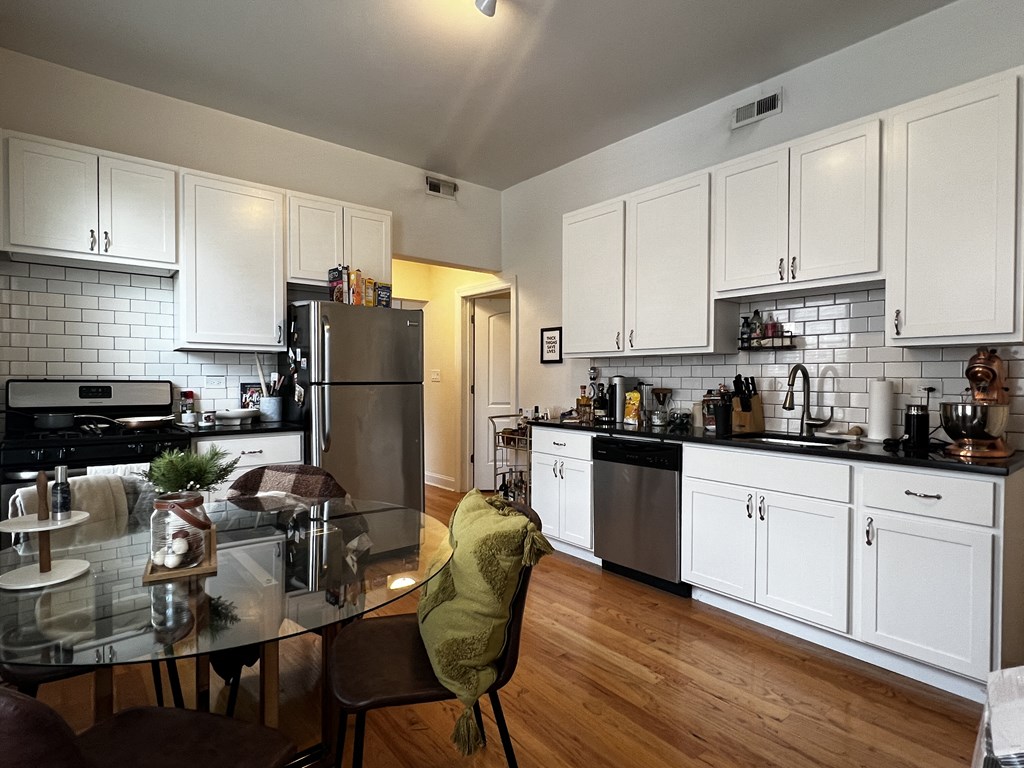 a kitchen and dining room with white cabinets and stainless steel appliances