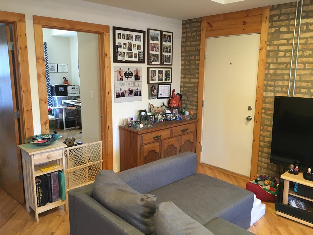 A living room with a grey couch and a wooden cabinet.