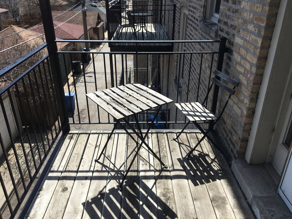 A table and two chairs are on a balcony.