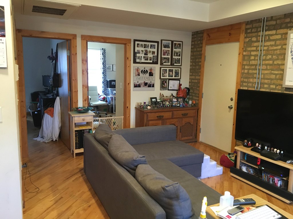 A living room with a grey couch and a wooden floor.