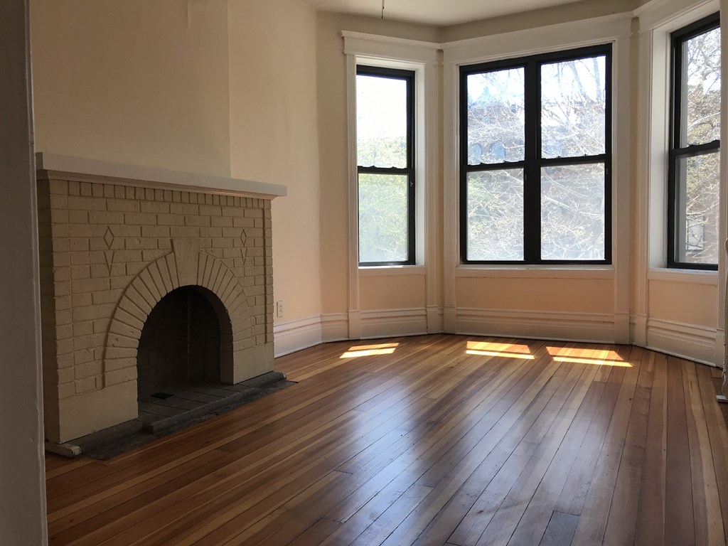 A room with a fireplace and wood flooring.