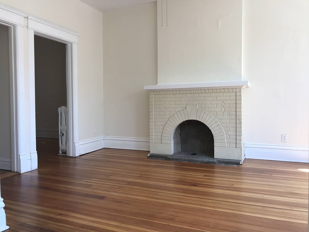 A room with a fireplace and wooden floors.