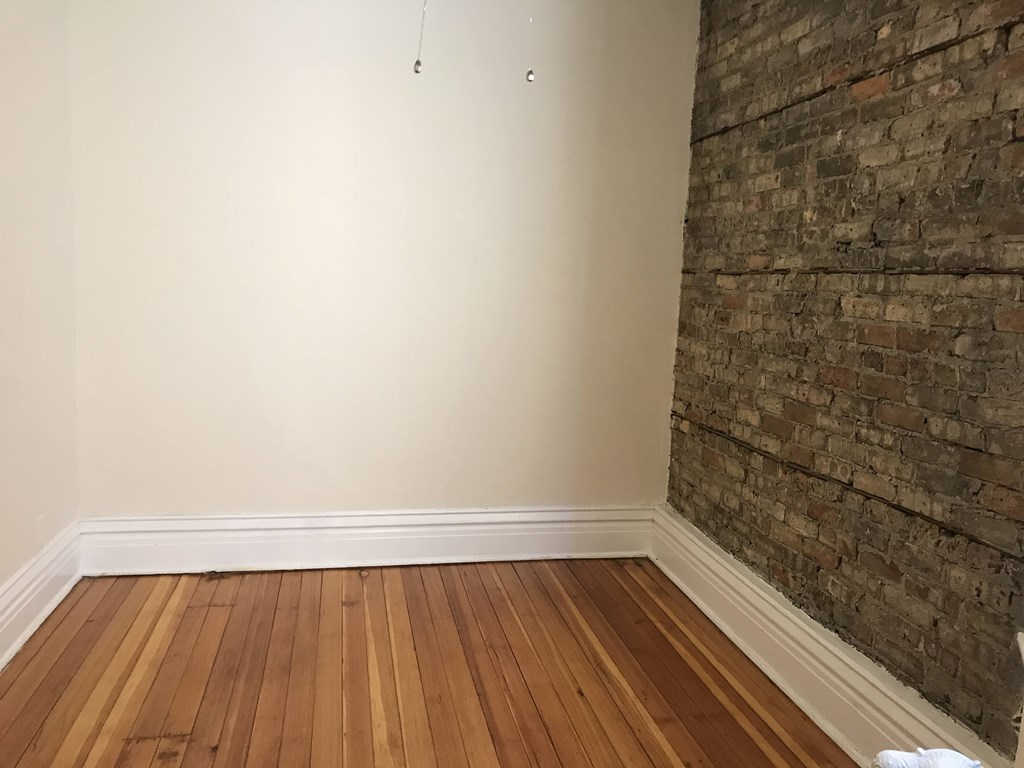 A room with a wooden floor and a brick wall.