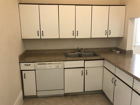 A kitchen with white cabinets and a granite countertop.