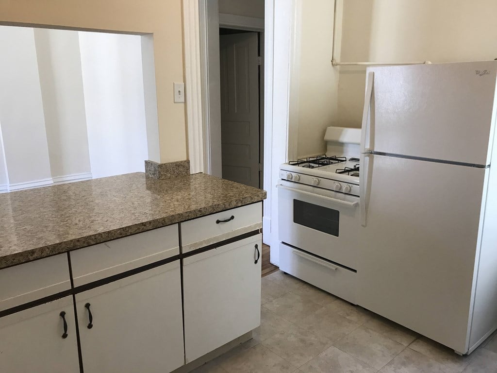 A kitchen with a granite countertop and white cabinets.