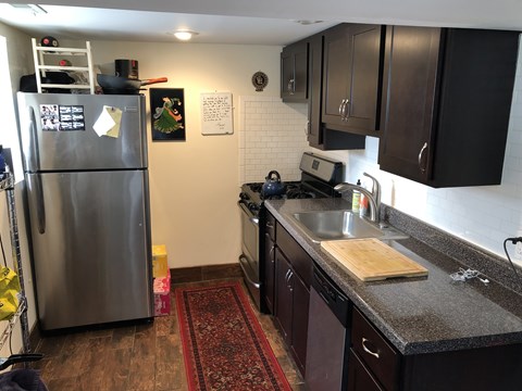 A kitchen with a stainless steel refrigerator and dark brown cabinets.