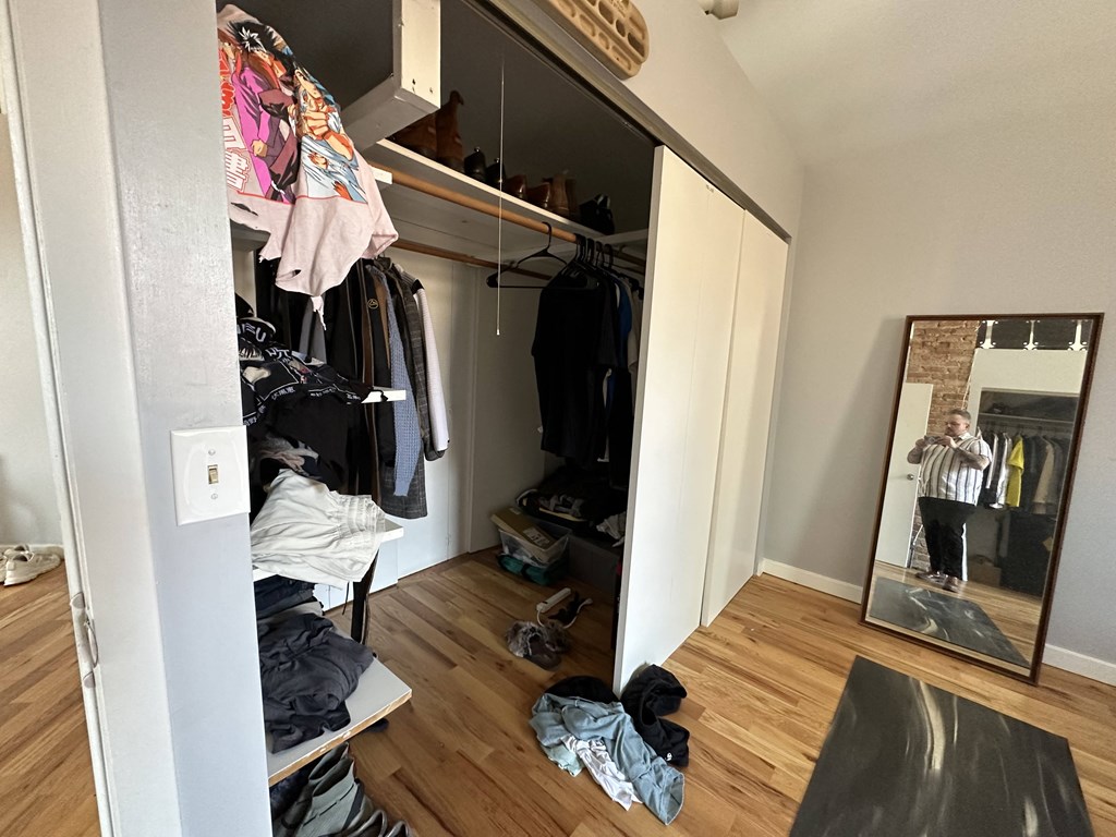 a walk in closet with a mirror and a dresser with clothes in it