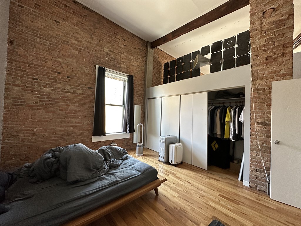 a bedroom with a bed and a brick wall and a closet