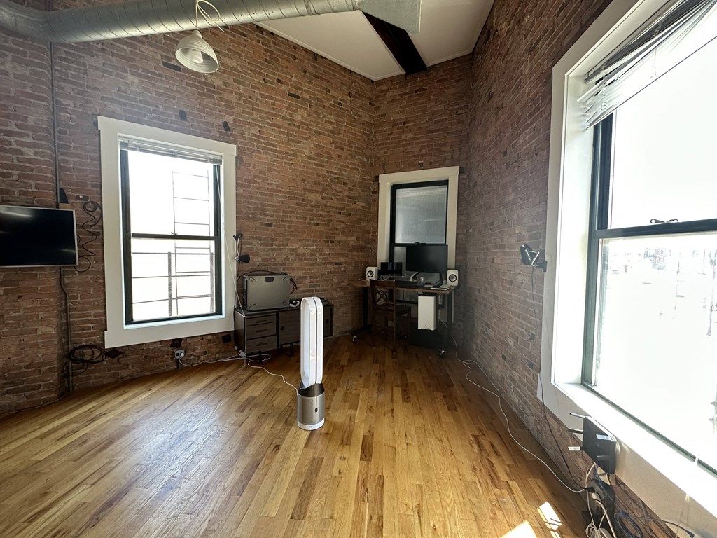 an empty room with a wood floor and two windows