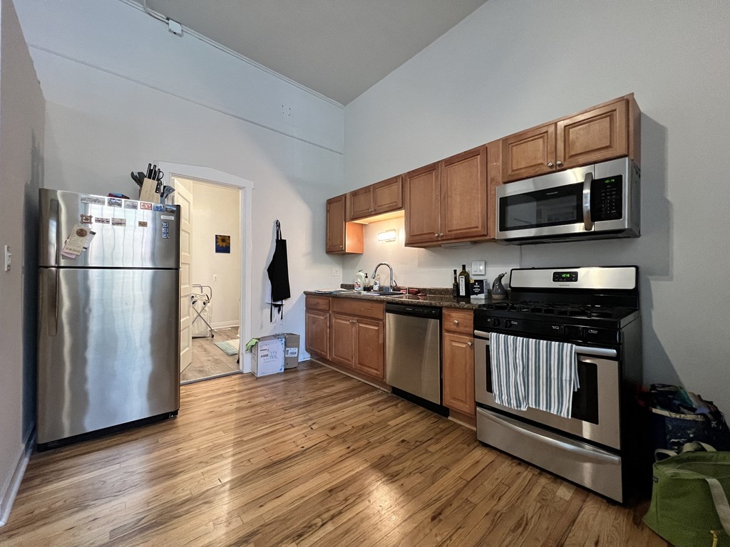 an empty kitchen with stainless steel appliances and wooden floors