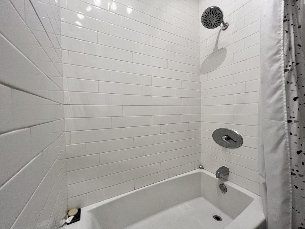 a white tiled bathroom with a shower and a tub