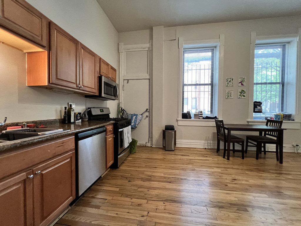 a kitchen and dining room with wood floors and wooden cabinets
