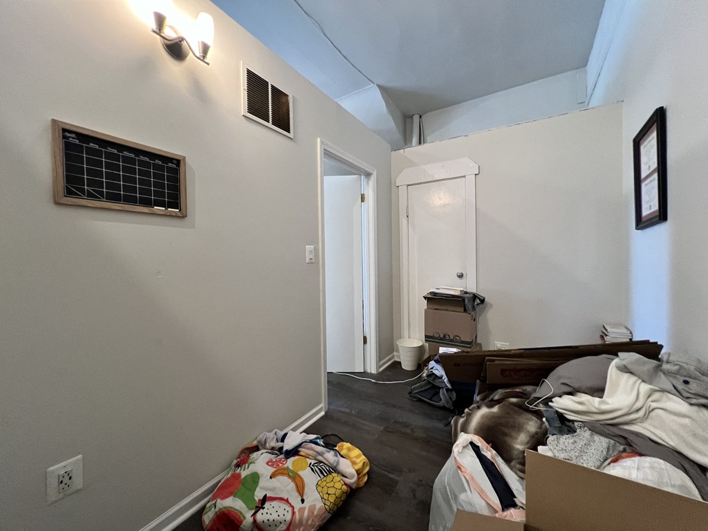 a bedroom with a pile of clothes on the floor and a bed in a room