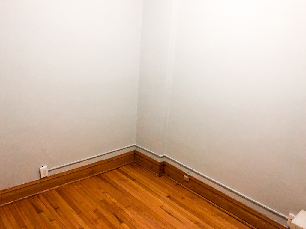 a corner of a room with wood floors and white walls