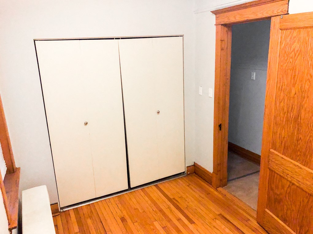 a closet in a room with wooden floors and a door