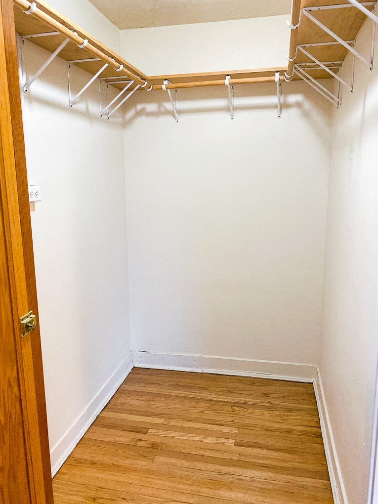 an empty closet with white walls and a wooden floor