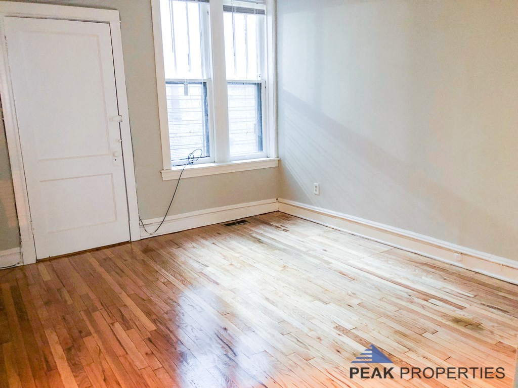 a room with wood floors and white walls and a window