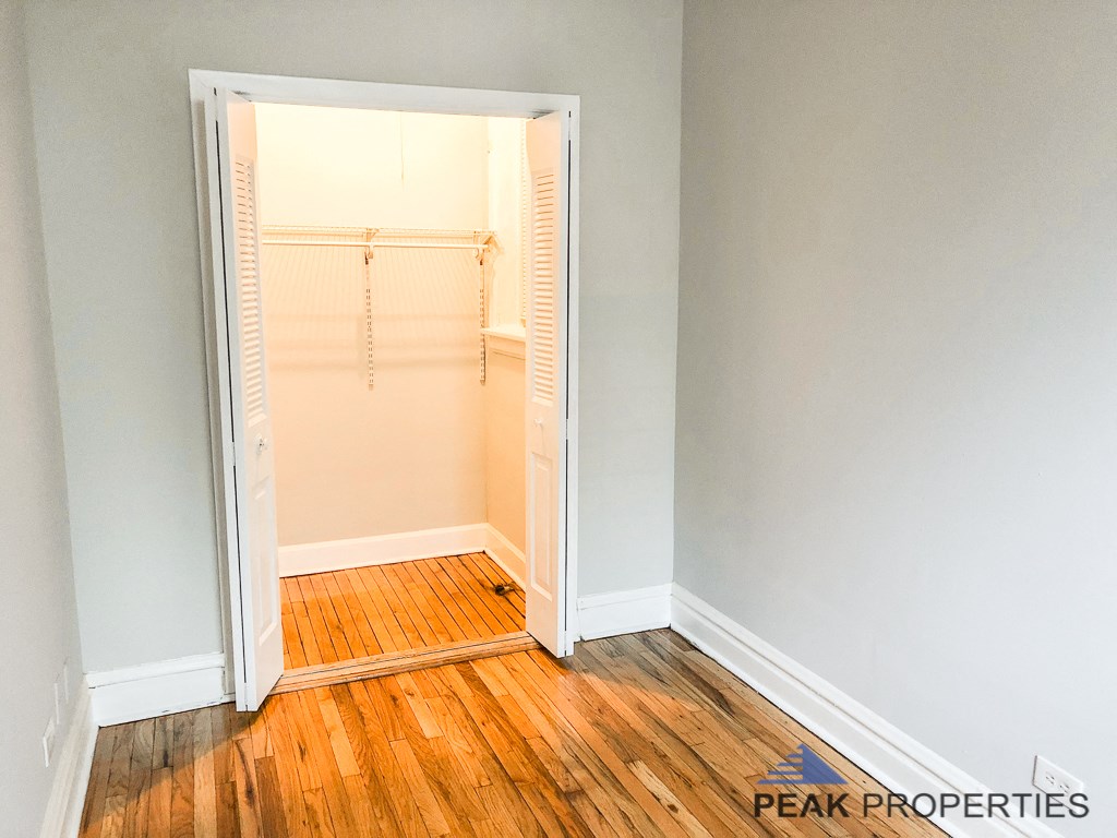 a closet in a small room with a wooden floor and an open door