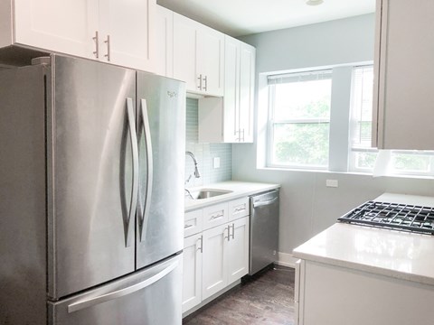 A modern kitchen with a stainless steel refrigerator and white cabinets.