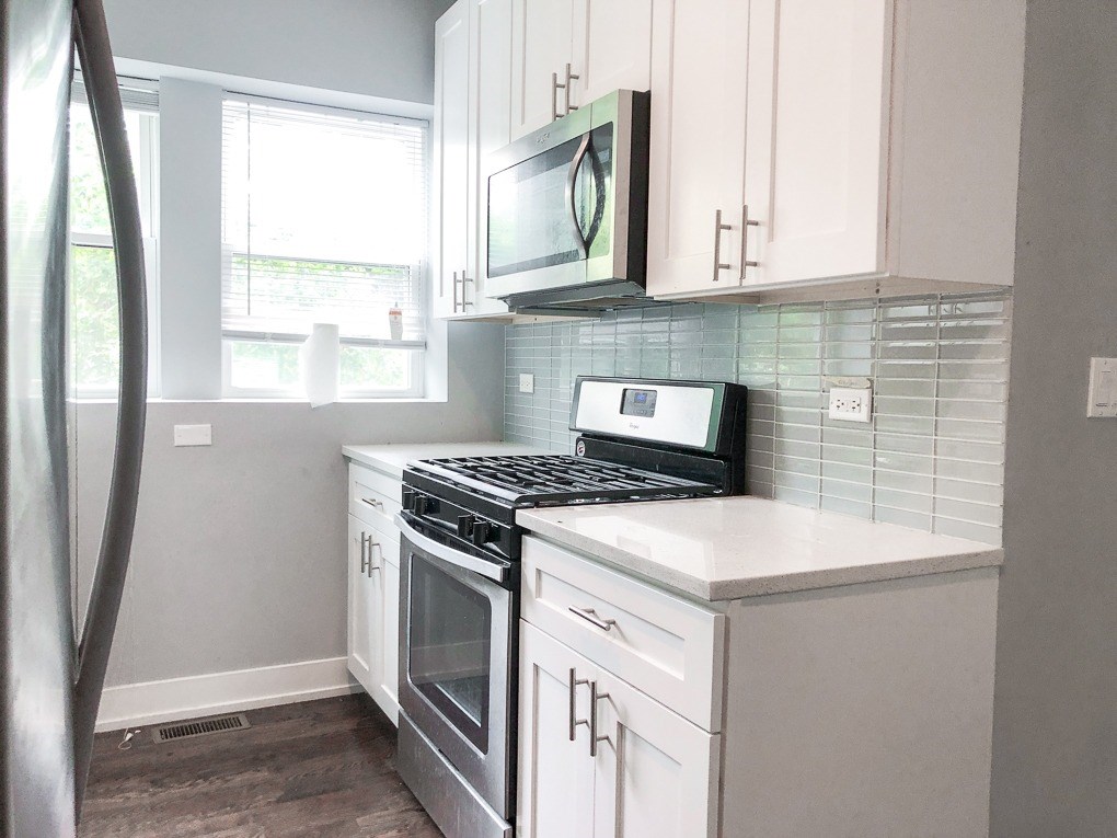 A kitchen with white cabinets and a black stove top oven.