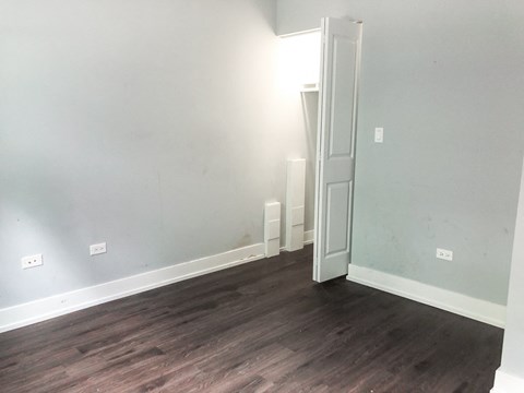 A room with a white door and wooden flooring.