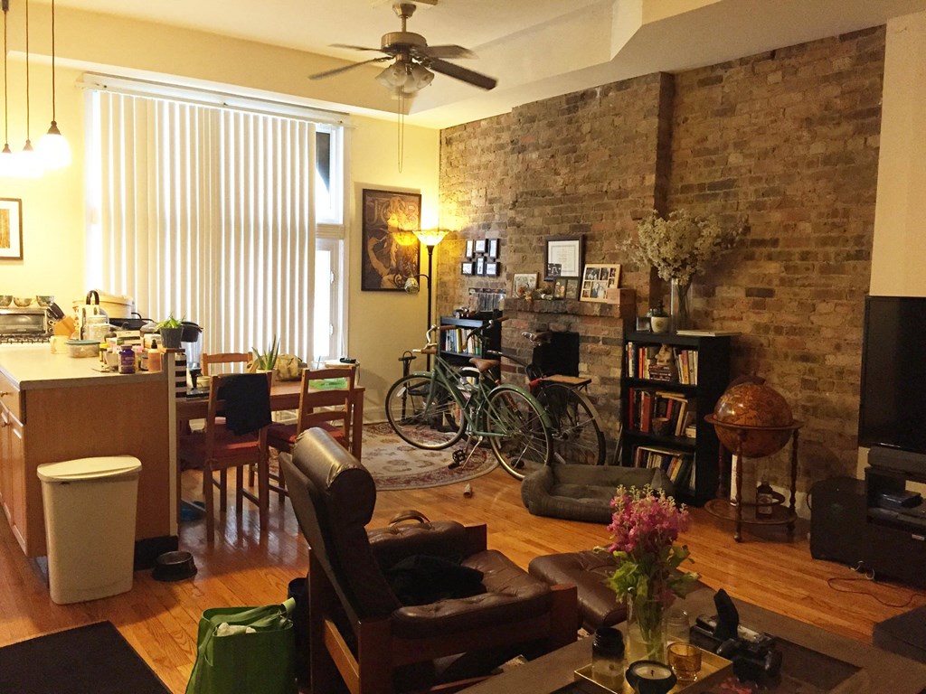 a living room and dining room with a brick wall and a bicycle