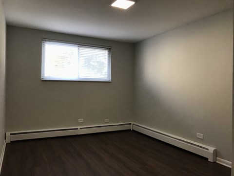 A room with a window and a radiator on the floor.