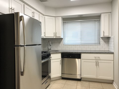 A kitchen with a black refrigerator and white cabinets.