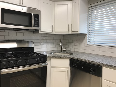 A kitchen with a black stove top oven and a black dishwasher.