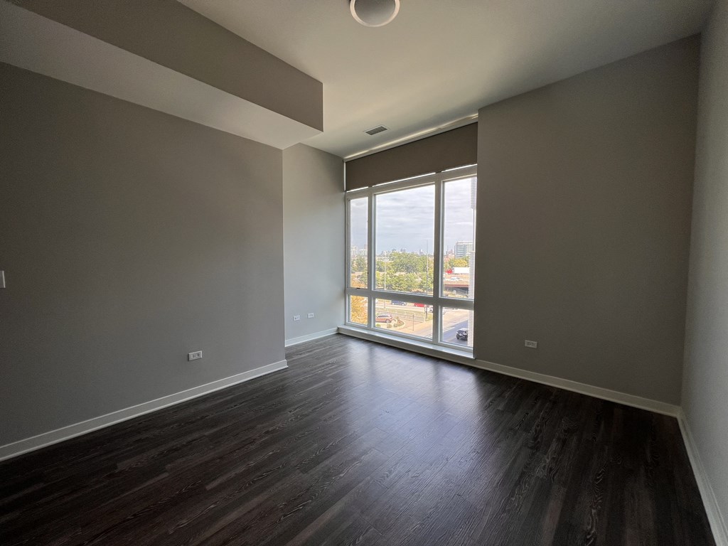 an empty living room with wood floors and a window
