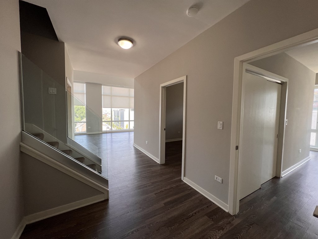 a view of a living room and a hallway with wood floors and a mirrored door