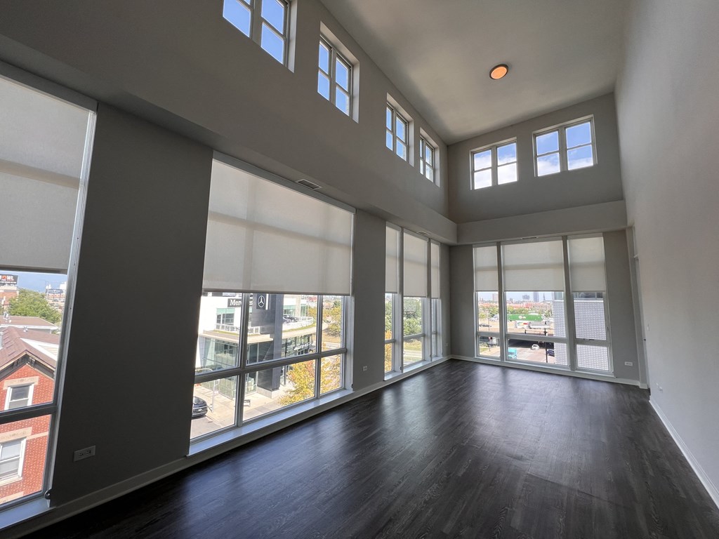 an empty living room with large windows and wood floors