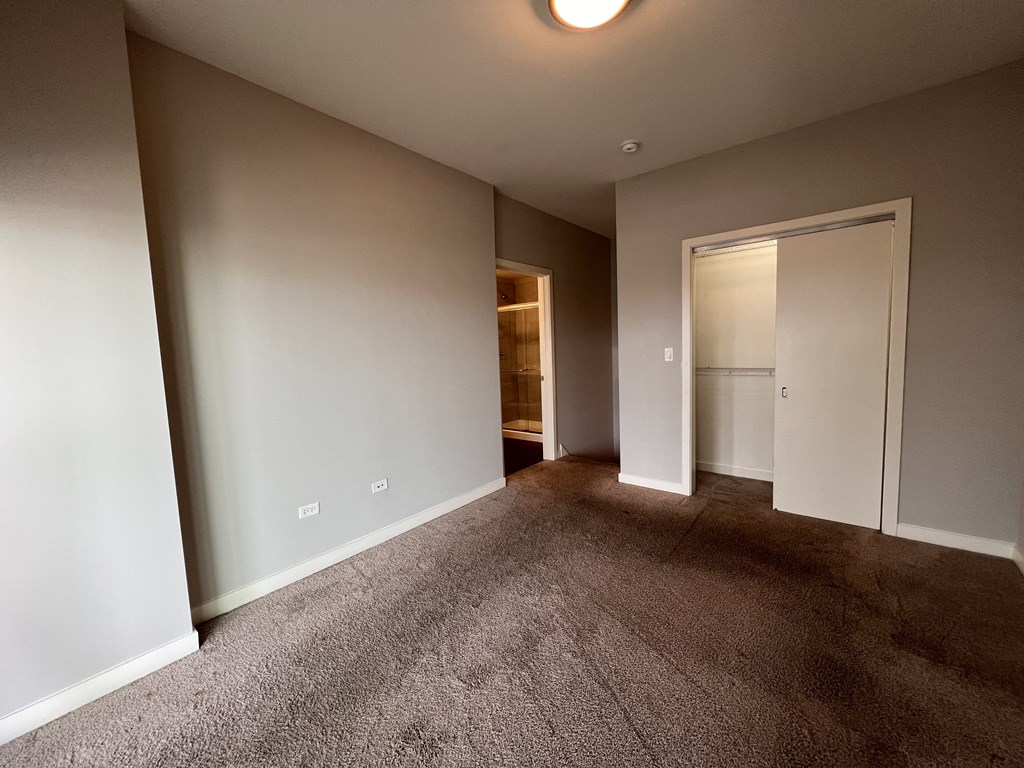 an empty living room with carpet and a door to a closet