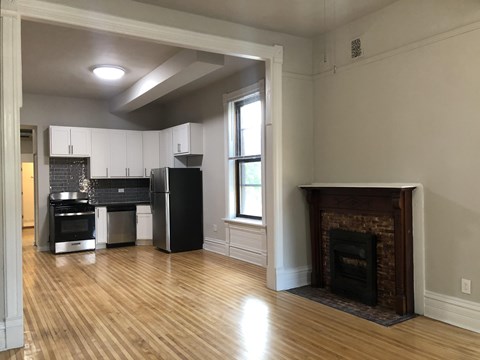 A kitchen with a fireplace and wooden floors.