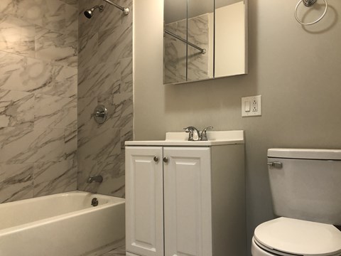 A white bathroom with a marble wall and a white tub.