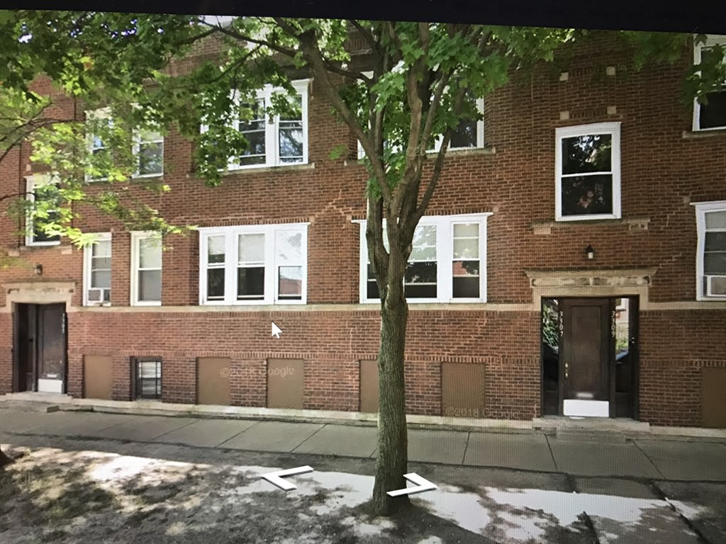 the front of a brick building with a tree in front