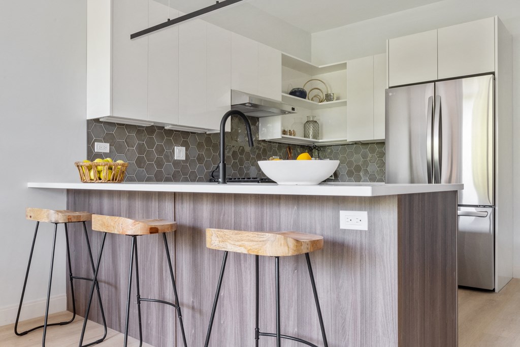 a kitchen with white cabinets and a gray counter top with a sink and three stools