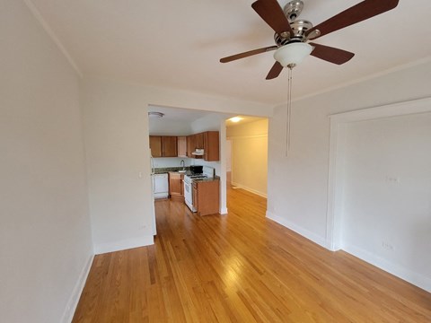 an empty living room with a ceiling fan and a kitchen