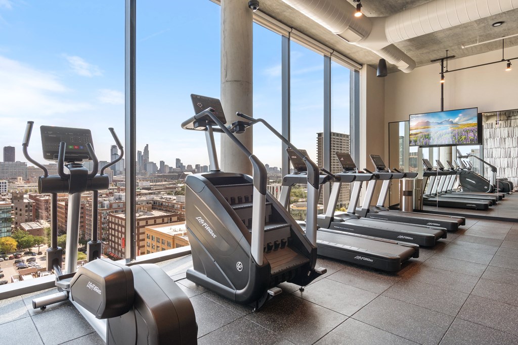 a gym with cardio machines and a view of the city
