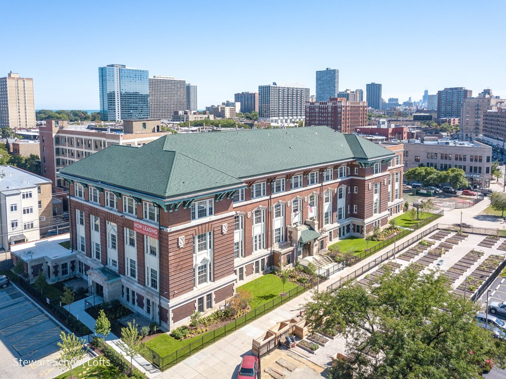 a large brick building with a green roof and a city in the background