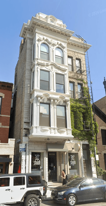 A tall building with a car parked in front of it.