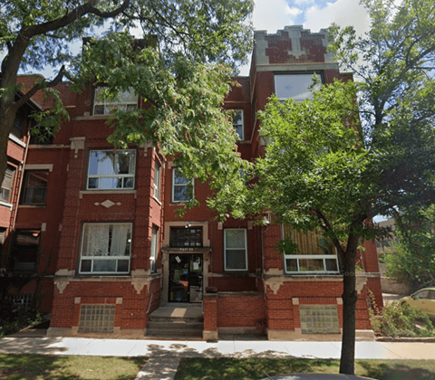 A red brick building with a tree in front.