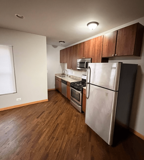 A kitchen with a refrigerator, oven, and microwave.