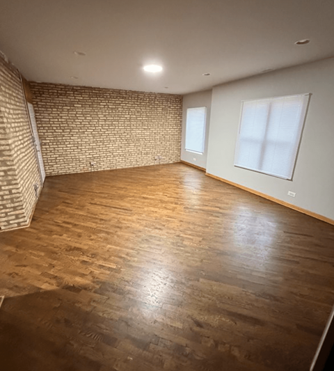 A room with wooden flooring and a brick wall.
