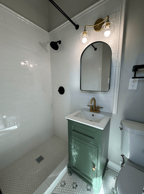 A bathroom with a green vanity and a white toilet.