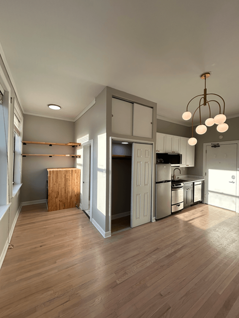 A kitchen with a wooden floor and a chandelier hanging from the ceiling.